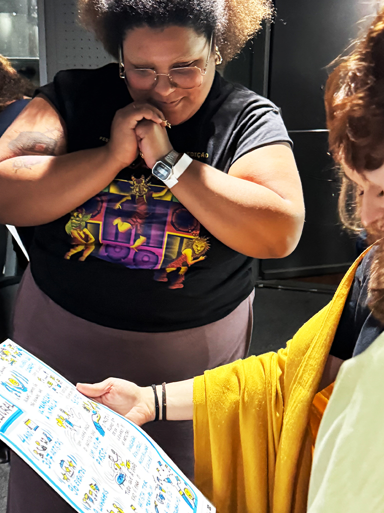 Empreendedora a olhar atentamente e com emoção para a prancha de facilitação gráfica com ilustrações azuis durante o evento Caminhos Criativos.